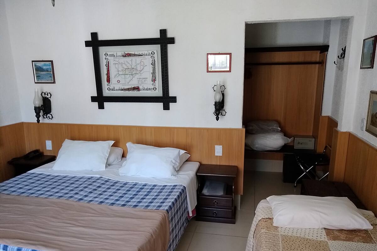 A hotel room with a large bed, a smaller bed, a wooden headboard, a map on the wall, and a closet.