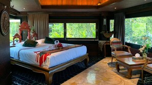 Un dormitorio amplio con una cama grande, techo de madera y vistas a exuberante vegetación.