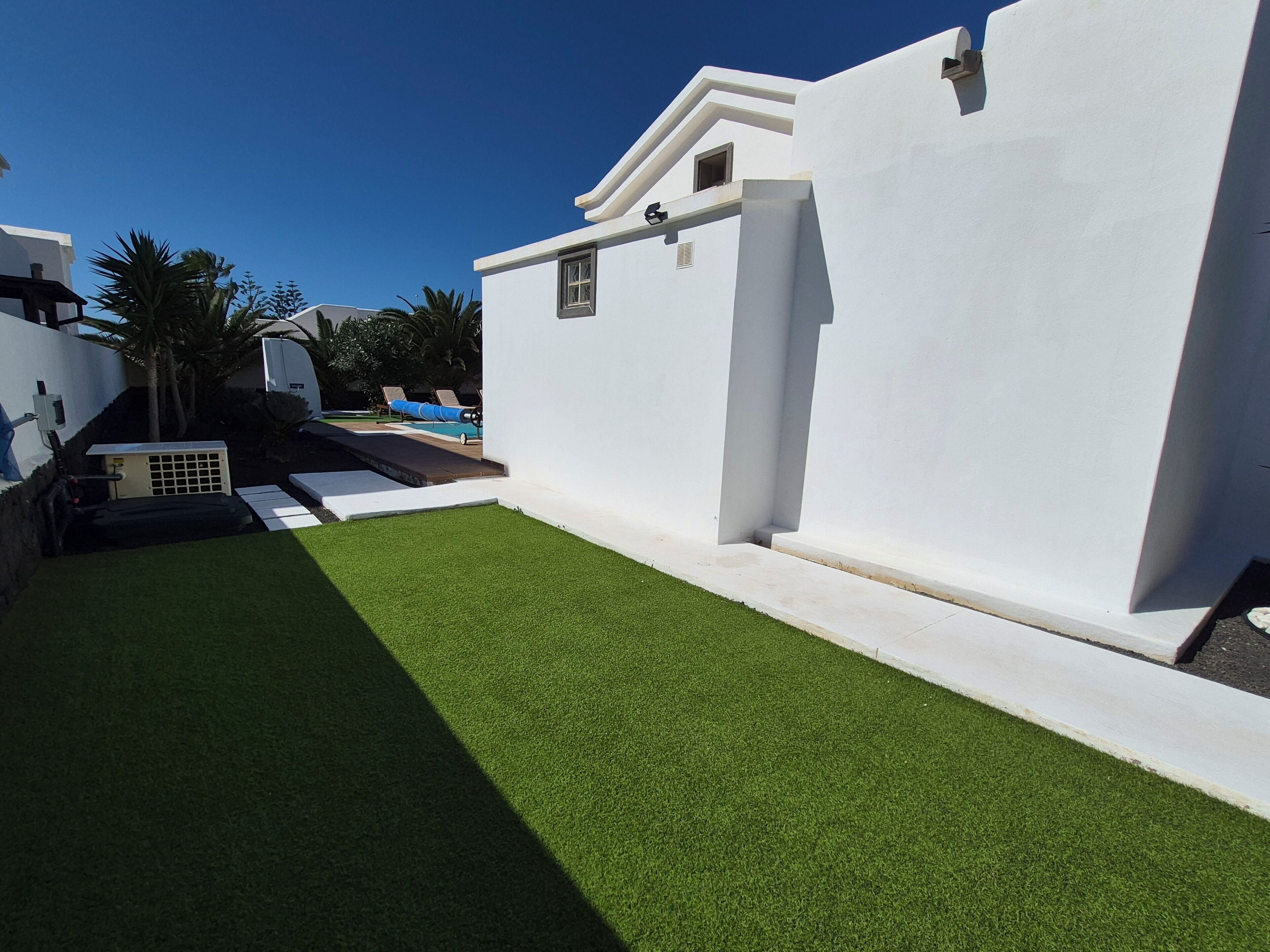 Un bâtiment moderne à l’extérieur blanc, doté d’une petite fenêtre et d’une porte.