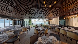 A restaurant with a modern interior, featuring wooden ceiling panels and tables set for dining. - Parosand Danang Hotel (Da Nang)