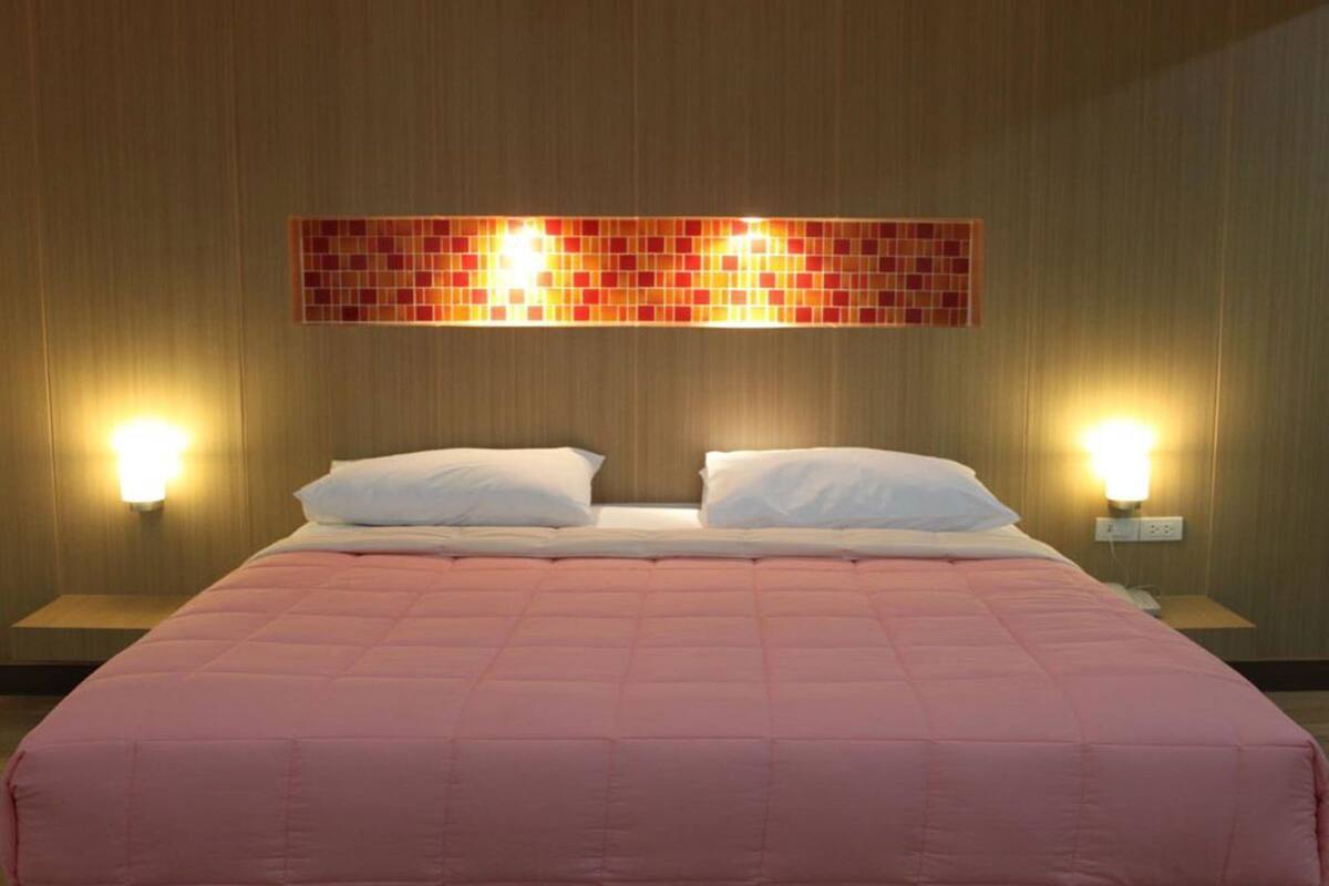 Una camera d'albergo con un letto, due lampade da comodino e un punto luce a parete.