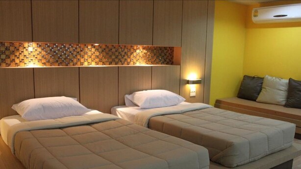 A hotel room with two beds, a sofa, and a decorative wall panel.