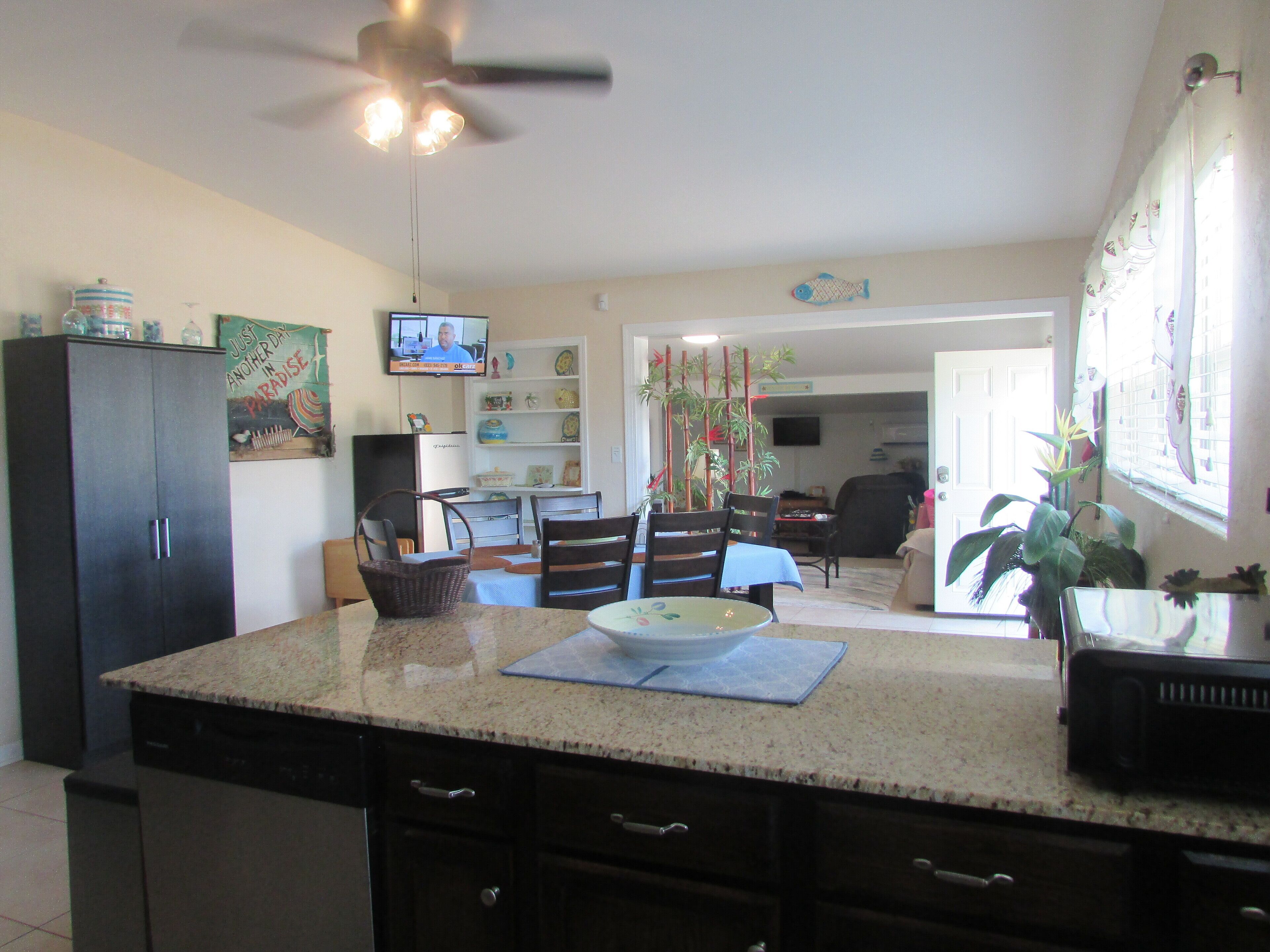 A kitchen with a granite countertop, dark cabinets, and a ceiling fan.