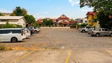 Um estacionamento com vários veículos, incluindo uma minivan branca e uma caminhonete prateada.