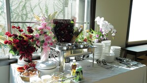 A buffet setup with various food items, a flower arrangement, and dining utensils. - Day Hotel Khon Kaen (Khon Kaen)