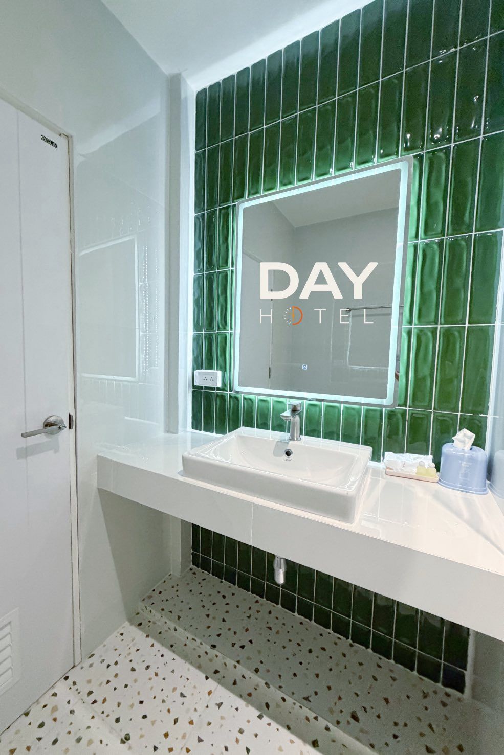 A bathroom with a white sink, green tiled walls, and a mirror with "DAY HOTEL" text.