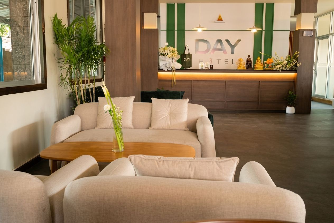 A hotel reception area with a reception desk, a sofa, a coffee table, and a potted plant.