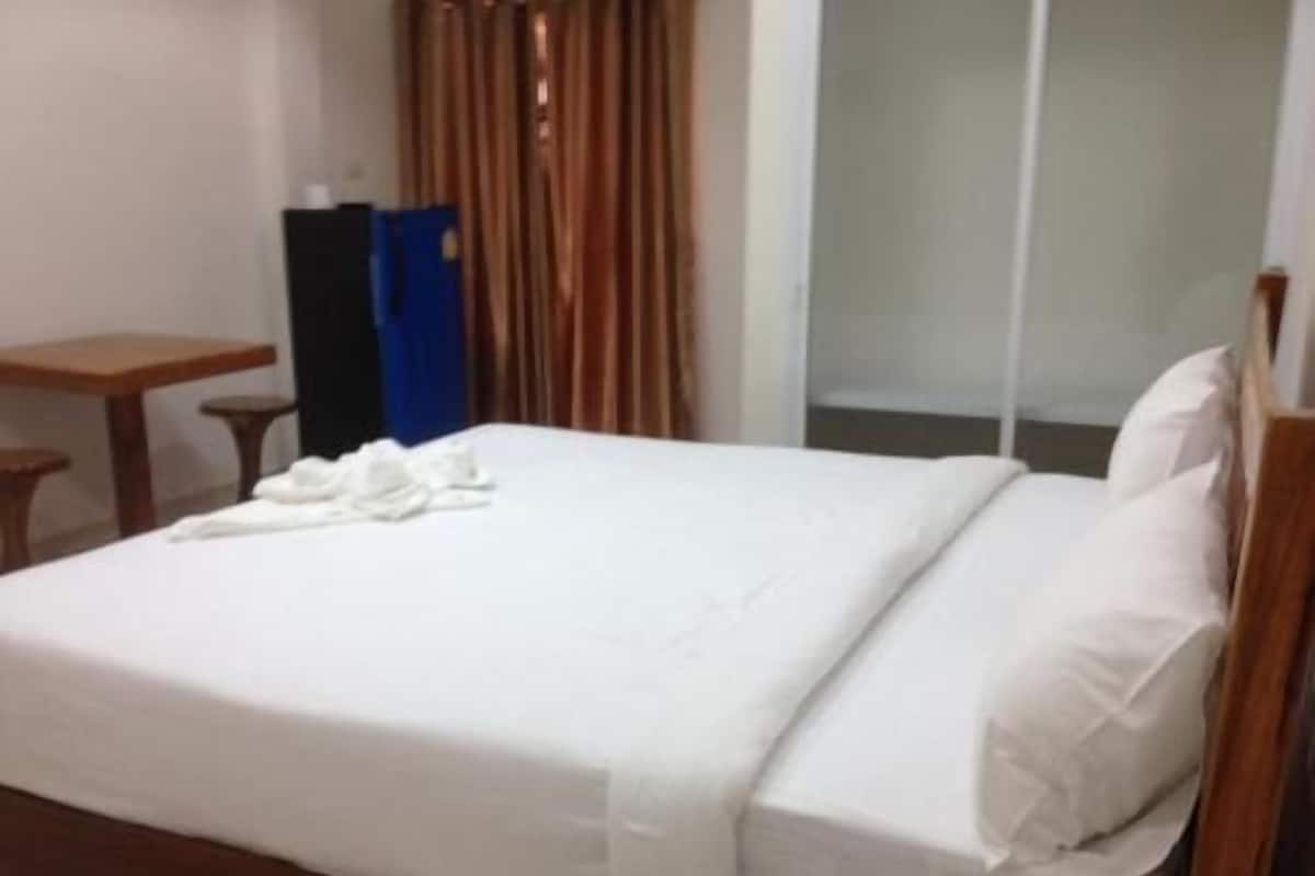 A hotel room with a bed, a small table, and a curtain.