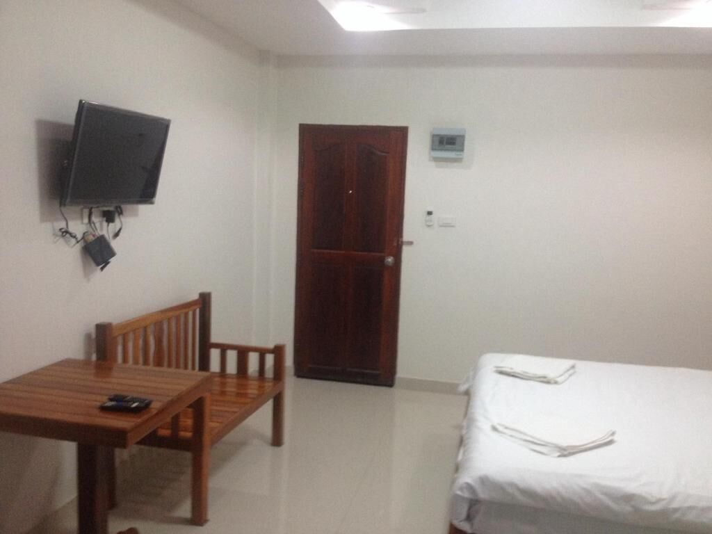A room with a bed, a desk with a chair, a television mounted on the wall, and a door.