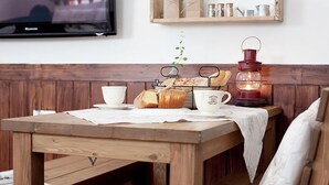A wooden table with a white tablecloth, a cup, a teapot, a tray of bread, and a lit lantern. - Princess Pension (Gyeongju)