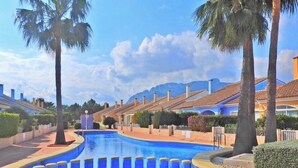 A swimming pool with blue water, surrounded by palm trees and a mountain in the background. - Beautiful apartment near the beach with a view of the pool and the mountain 'Segaria' (El Verger)