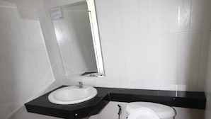 A bathroom with a white toilet, a sink, and a mirror. - Wangthong Beach Resort (Laem Sing)