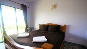 A bedroom with a large bed, a small table, and a window with curtains. - Wangthong Beach Resort (Laem Sing)