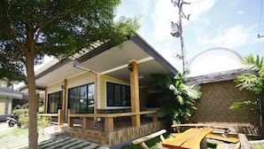 A building with a covered patio area, outdoor seating, and a stone wall. - Wangthong Beach Resort (Laem Sing)