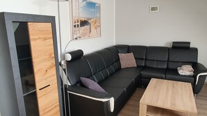 Un salon moderne avec un canapé en cuir noir, une table basse en bois et un lampadaire.