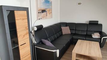 Ein modernes Wohnzimmer mit einer schwarzen Ledersofa, einem Holztisch und einer Stehlampe.