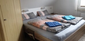 A double bed with patterned bedding and two blue towels.