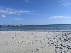 Une plage avec une jetée qui s’avance dans l’océan.