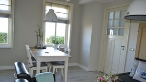 A dining area with a white table and chairs, a bench with a cushion, a potted plant, and a sofa with a cushion. - Cozy and Komfortale holiday property, former farm (Oostkapelle)