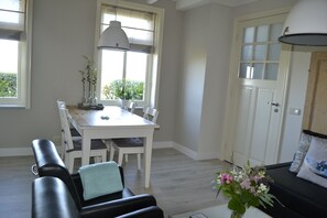 A dining area with a white table and chairs, a bench with a cushion, a potted plant, and a sofa with a cushion.