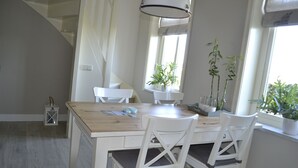A dining area with a wooden table, white chairs, and potted plants. - Cozy and Komfortale holiday property, former farm (Oostkapelle)