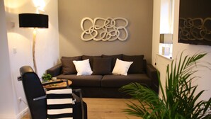 A modern living room with a dark brown sofa, two white pillows, a black and white striped chair, a floor lamp, and a wall art piece. - Sealounge Vacation Home Near the Beach, Sauna, Beach Chair, Free Wi-Fi - SEASIDE - (Rosenhagen)