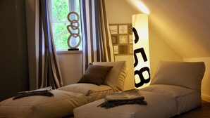 A room with two beige sofas, a window with curtains, and a wall with framed pictures and a lamp. - Sealounge Vacation Home Near the Beach, Sauna, Beach Chair, Free Wi-Fi - SEASIDE - (Rosenhagen)