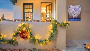 A hotel entrance with a Christmas wreath and lights, a sign reading "Inn of the Laughing Llama," and a view of the interior through the door. - Pristine, art-filled Home 2 blocks to Historic Santa Fe Plaza. Read the reviews! (Santa Fe)