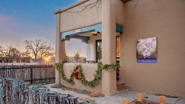 A building with a beige exterior, a blue awning, and a sign that reads "Inn of the Laughing Llama." - Pristine, art-filled Home 2 blocks to Historic Santa Fe Plaza. Read the reviews! (Santa Fe)