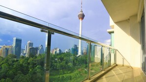 A balcony with a glass railing overlooking a cityscape, including a prominent tower and dense greenery. - AirPorter Bukit Bintang Residence (Kuala Lumpur)
