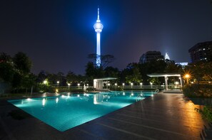 A nighttime swimming pool with a tower in the background. - AirPorter Bukit Bintang Residence (Kuala Lumpur)