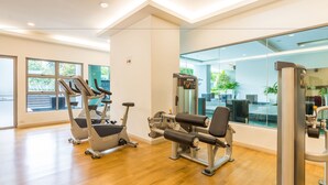 A modern gym with cardio machines, weight training equipment, and large windows offering natural light and views of the outdoors. - AirPorter Bukit Bintang Residence (Kuala Lumpur)