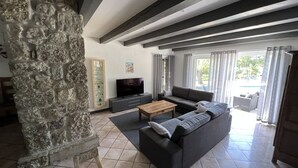 Ein Wohnzimmer mit einer Steinsäule, einem Sofa, einem Fernseher und einem Holztisch.