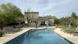 Ein rechteckiger Pool mit einem Steinhaus im Hintergrund.
