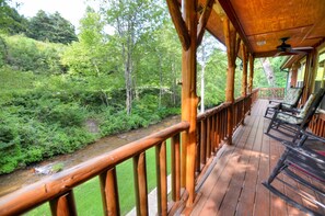 A wooden deck with a view of a forested area and a stream. - Cute Cabin On The Creek Near Dillsboro (Sylva)