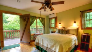 Un dormitorio con una cama grande, un ventilador de techo, una ventana con cortinas y vistas al exterior.