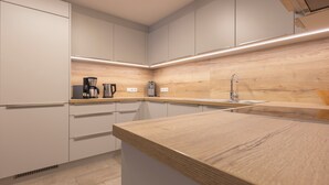 A modern kitchen with white cabinets, a wooden countertop, and built-in appliances. - Rental Ban Brösign - holiday idyll with style and modern comfort (Umhausen)