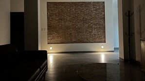 A modern interior with a brick wall accent, a dark leather sofa, and a marble coffee table.