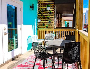 Patio esterno con tavolo rotondo e quattro sedie, recinzione in legno e piante in vaso.
