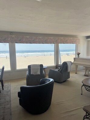 Una habitación con ventanas amplias, un piano y dos sillones.