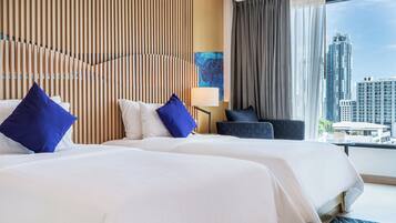 A hotel room with two beds, a city view, a modern wall design, and a lamp.