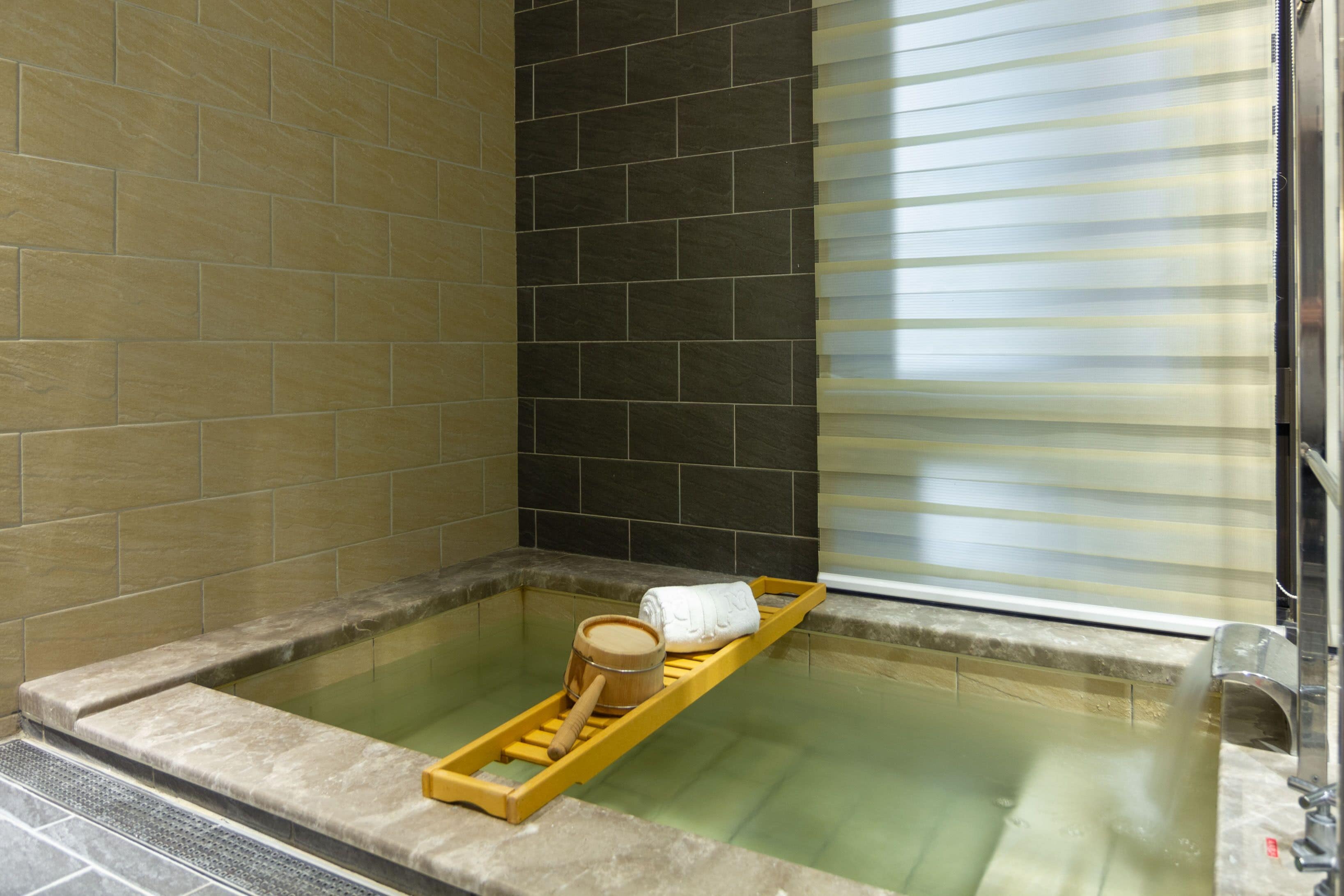 Bagno termale con un vassoio di legno, un catino di legno e un asciugamano.