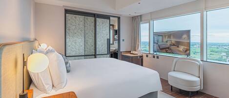 Une chambre d’hôtel moderne avec un grand lit, un bureau, une chaise et une vue sur la ville.