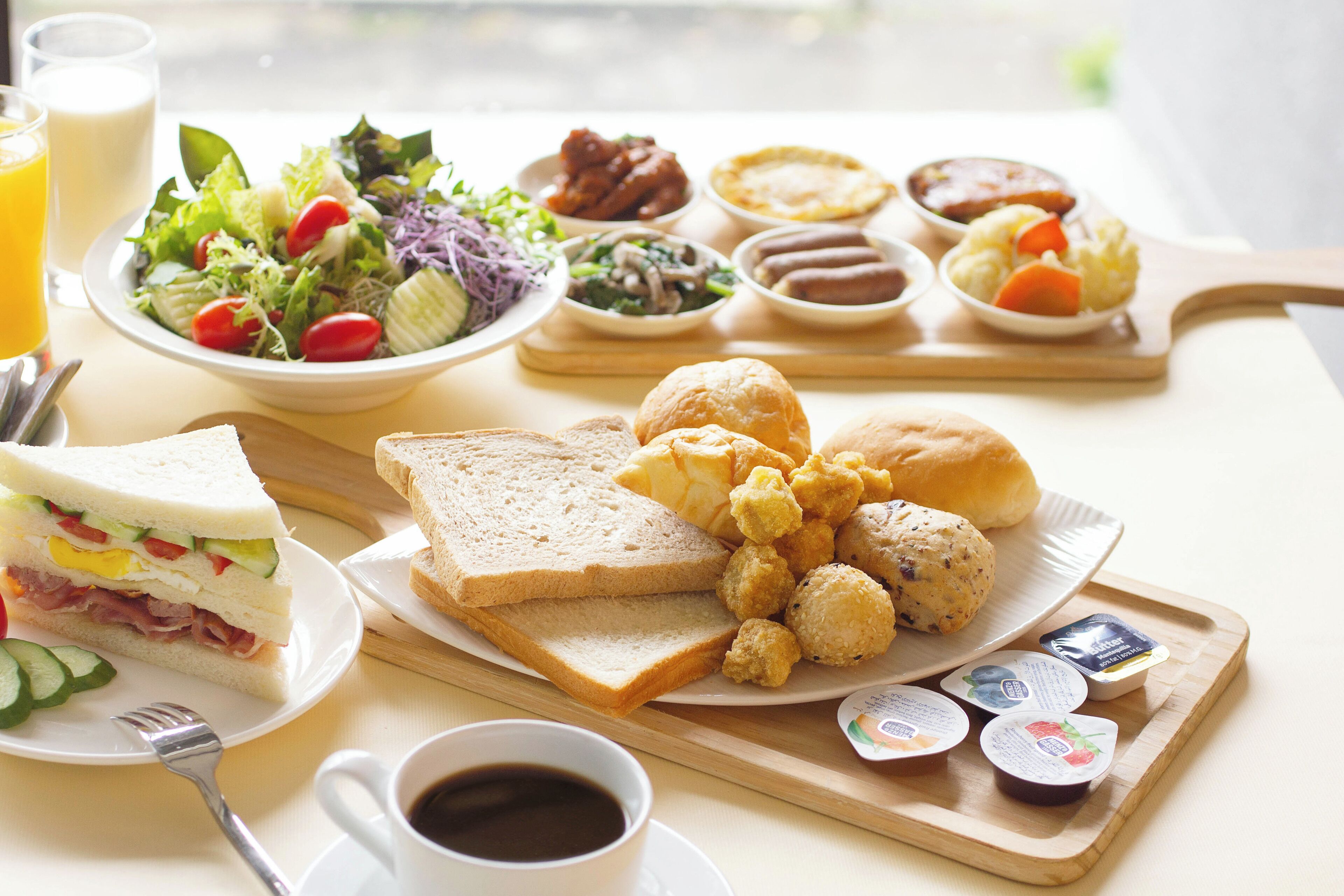 Un plateau de petit-déjeuner avec des toasts, des œufs, des saucisses et une salade.