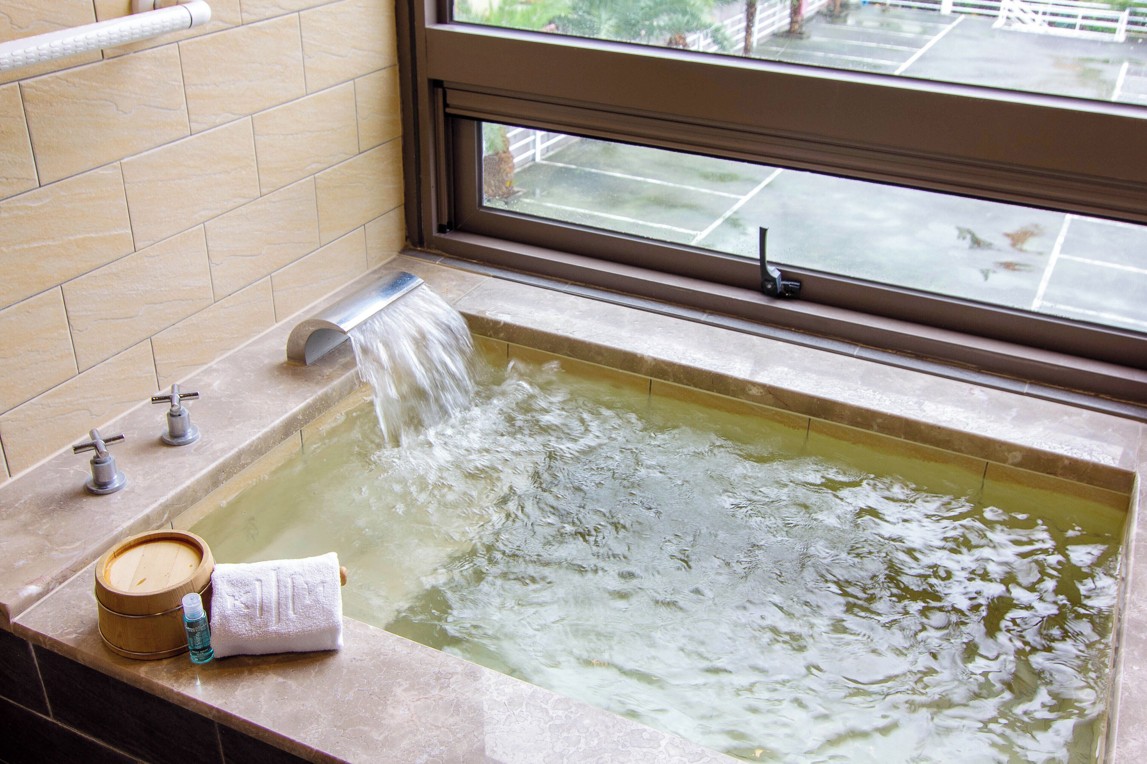 Una bañera con agua corriente, una toalla y una botella de champú.