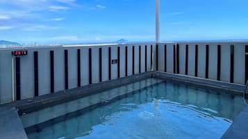 Una piscina en la azotea con vistas despejadas del horizonte urbano y montañas a lo lejos.