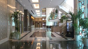A spacious lobby with a high ceiling, polished floors, and potted plants. - Kilin Hotel, JiaoXi (Jiaoxi)