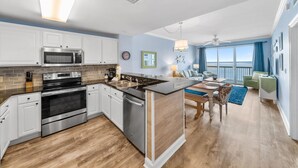 A modern kitchen with stainless steel appliances, a central island, and a dining area with a view of the ocean.