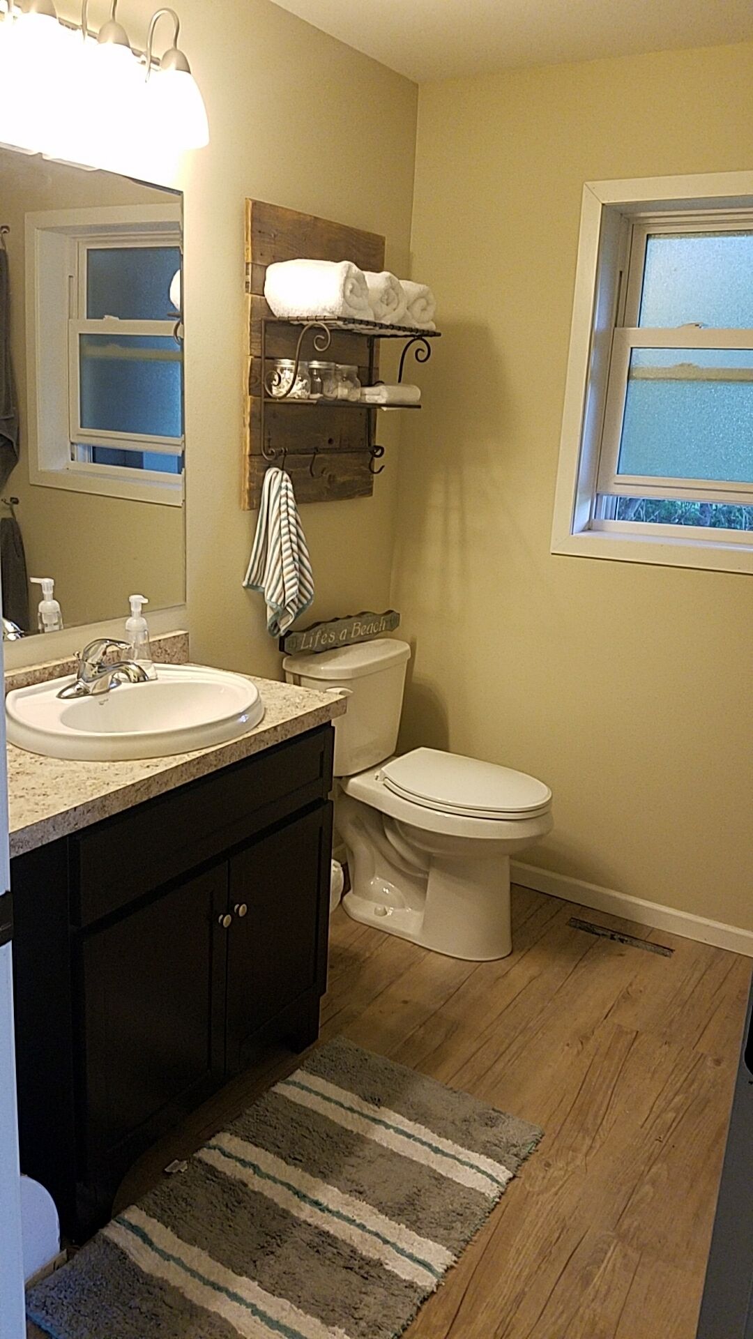 Une salle de bain avec un lavabo, des toilettes et une fenêtre.