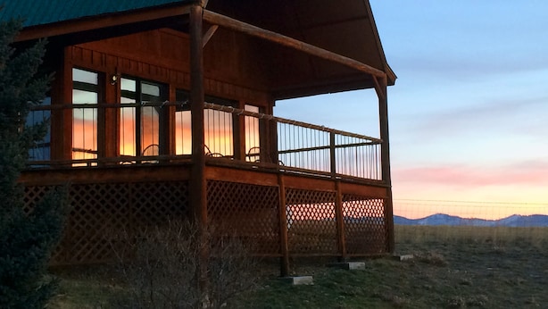 A wooden cabin with a green roof, a balcony with a lattice railing, and large windows. - Wilderness Spirit Cabins, LLC-'Eagle Nest'- Heavenly Mountain Views (Corvallis)